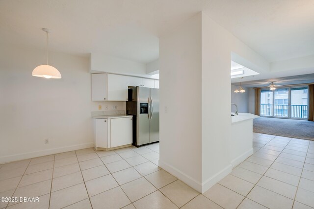 kitchen with stainless steel fridge, open floor plan, hanging light fixtures, light countertops, and white cabinetry