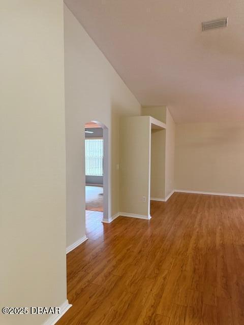 107 Beacon Mill Ln, Palm Coast, FL 32137 - spare room featuring arched walkways, wood finished floors, and vaulted ceiling