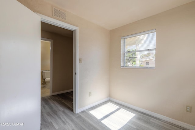 empty room featuring light wood-type flooring, baseboards, and visible vents