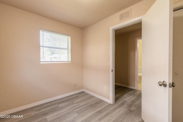 empty room with light wood-style floors, baseboards, and visible vents