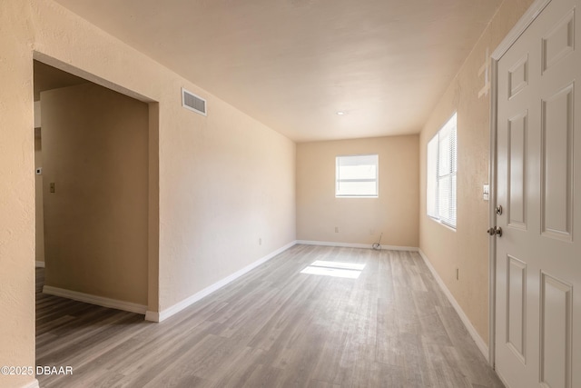 empty room with visible vents, baseboards, and wood finished floors