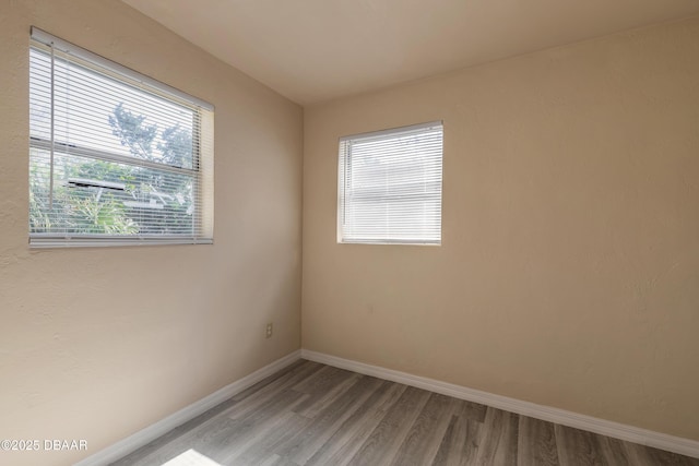 spare room with baseboards and wood finished floors