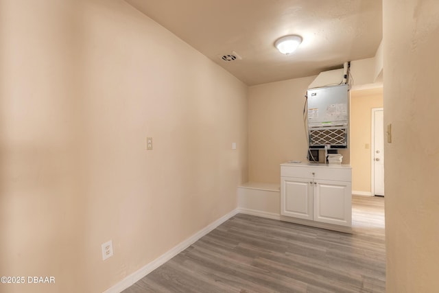 hallway featuring light wood-style flooring, visible vents, and baseboards