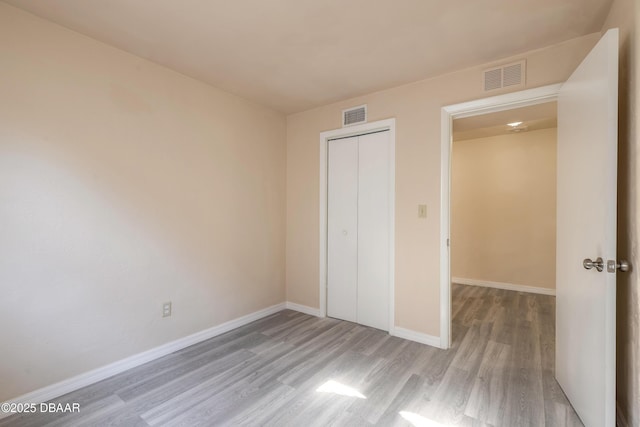 unfurnished bedroom with light wood-style flooring, a closet, visible vents, and baseboards