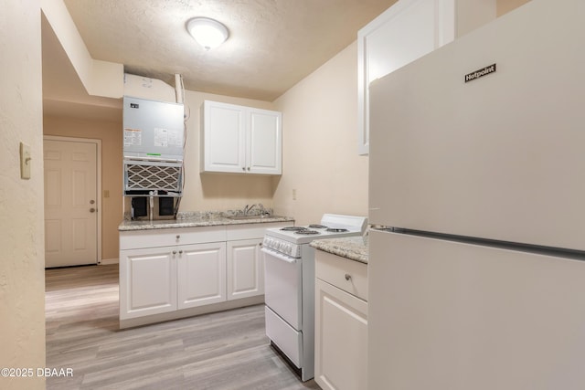 kitchen with white appliances, a textured ceiling, white cabinetry, and light wood-style floors