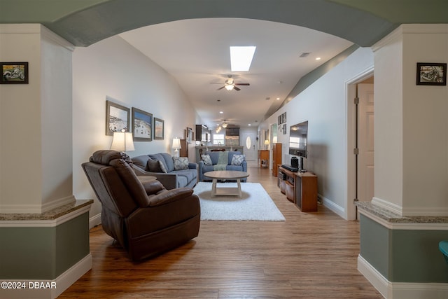 living room with vaulted ceiling with skylight, hardwood / wood-style flooring, and ceiling fan