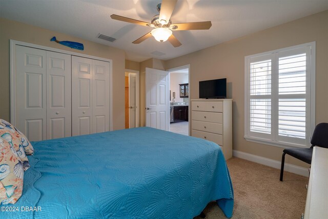 bedroom with ceiling fan, connected bathroom, a closet, and light colored carpet