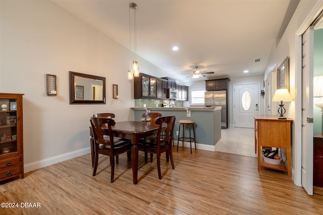 dining area featuring ceiling fan, sink, light hardwood / wood-style flooring, and lofted ceiling