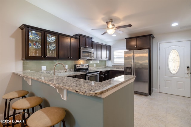 kitchen with backsplash, lofted ceiling, dark brown cabinetry, and stainless steel appliances