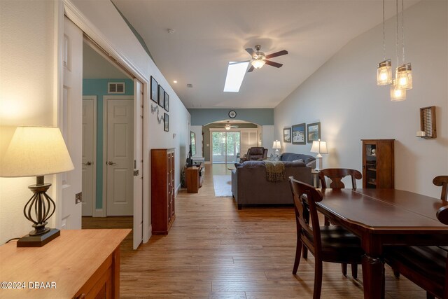 dining room featuring wood-type flooring, ceiling fan, and vaulted ceiling with skylight