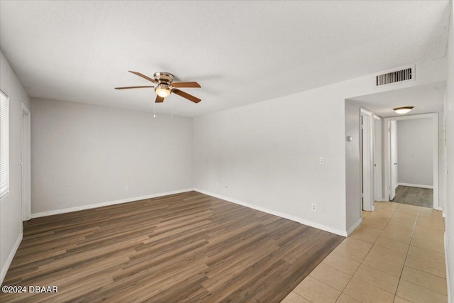 empty room with a textured ceiling, hardwood / wood-style flooring, and ceiling fan