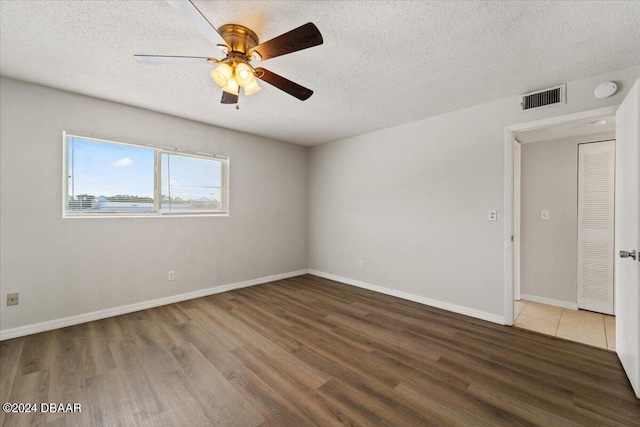 unfurnished room featuring visible vents, a ceiling fan, a textured ceiling, wood finished floors, and baseboards