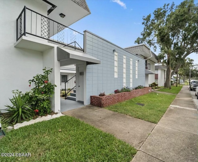 view of home's exterior with a lawn and a balcony