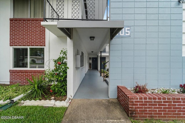 property entrance featuring brick siding, stucco siding, and a balcony