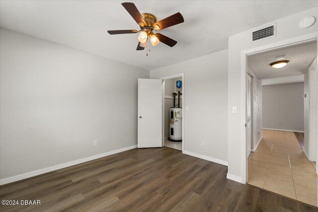 unfurnished room with ceiling fan, a textured ceiling, and dark hardwood / wood-style floors