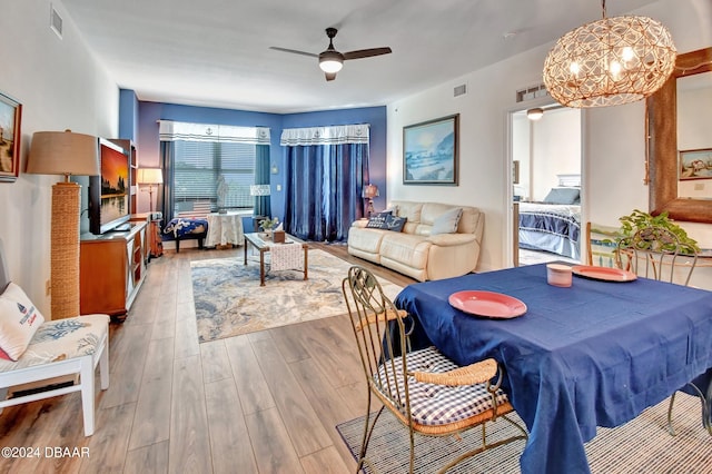 dining area featuring ceiling fan with notable chandelier and light hardwood / wood-style floors