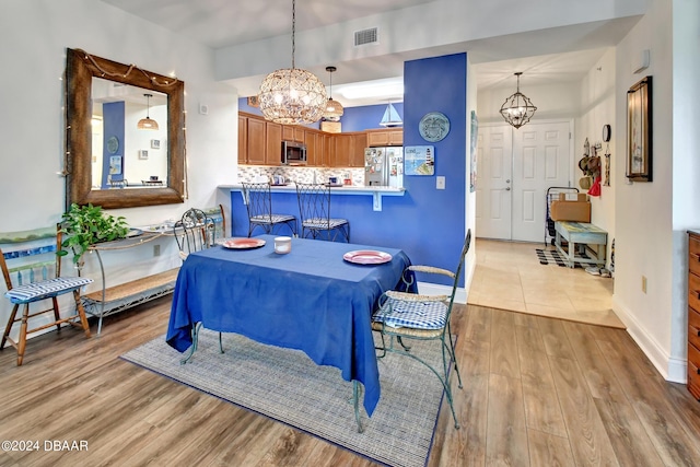 dining room with light hardwood / wood-style floors and an inviting chandelier