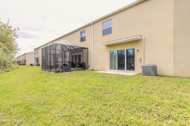 rear view of property with a lawn, central air condition unit, a lanai, and a patio area