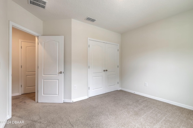 unfurnished bedroom with a closet, a textured ceiling, and carpet floors