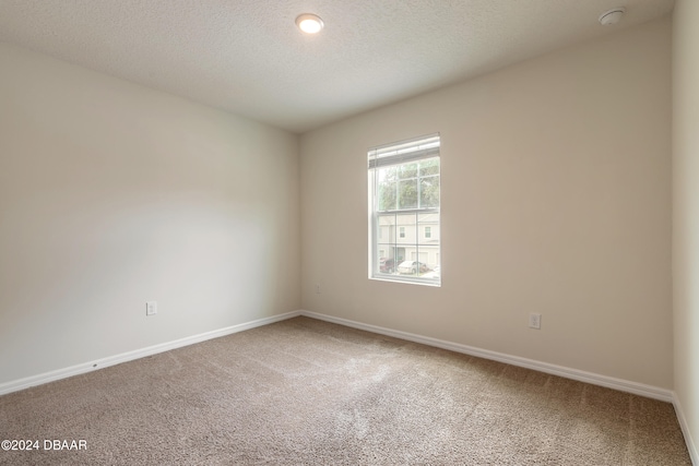 empty room with a textured ceiling and carpet floors