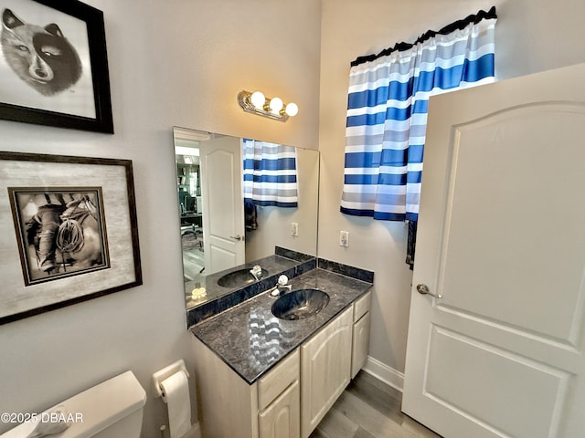 1811 N Central Ave, Flagler Beach, FL 32136 - bathroom featuring vanity, baseboards, wood finished floors, and toilet