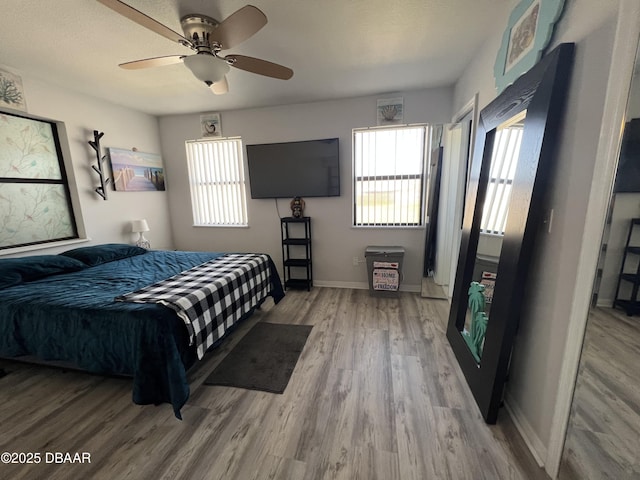 bedroom featuring baseboards, wood finished floors, and a ceiling fan