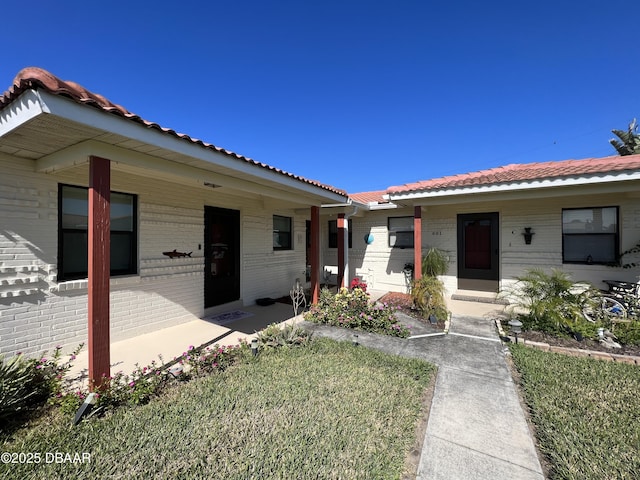 view of front of house with brick siding, covered porch, and a tiled roof