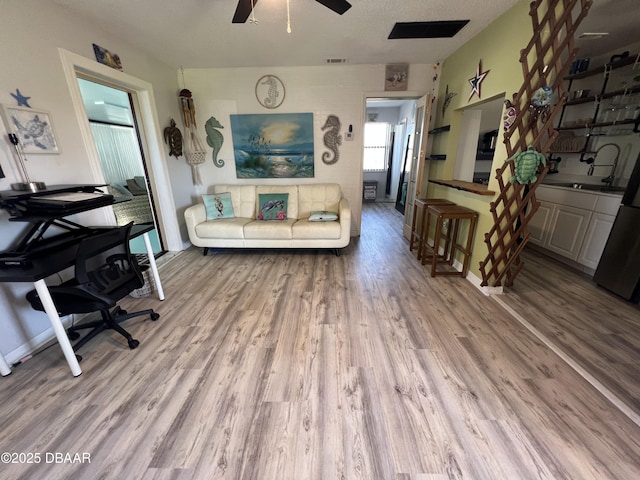 living area with visible vents, ceiling fan, and wood finished floors