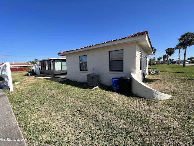 view of side of property featuring a yard, central air condition unit, and brick siding