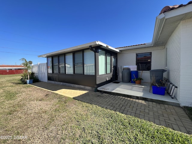 back of property with brick siding, a patio area, a lawn, and fence