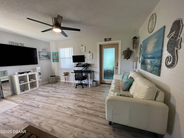 living room featuring a textured ceiling, ceiling fan, and wood finished floors