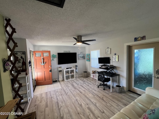 living area featuring a textured ceiling, light wood-type flooring, and ceiling fan