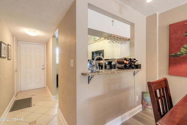 hallway featuring a textured ceiling and light tile patterned floors