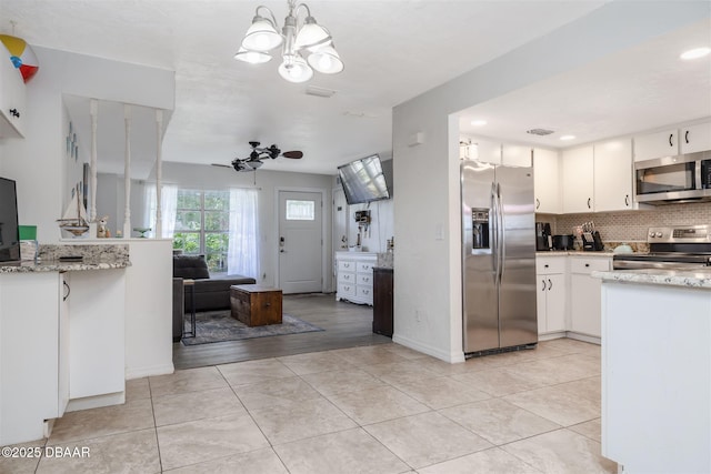 1052 Tompkins Dr, Port Orange, FL 32129 - kitchen featuring stainless steel appliances, decorative backsplash, white cabinetry, a chandelier, and light stone countertops