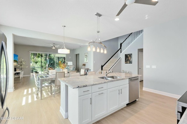 kitchen featuring stainless steel appliances, sink, light hardwood / wood-style floors, white cabinetry, and an island with sink