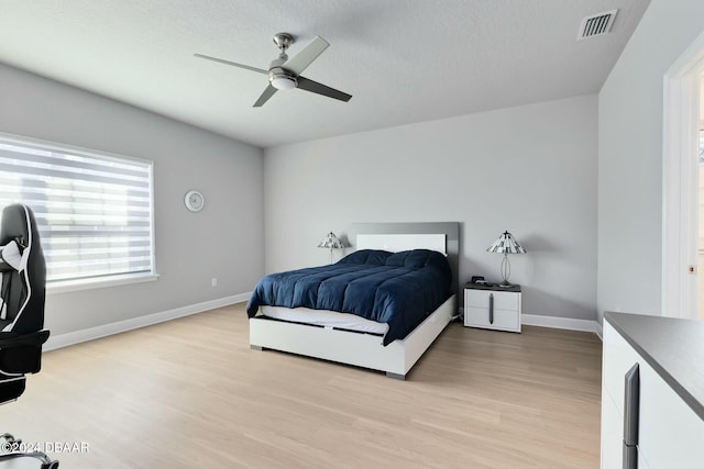 bedroom featuring ceiling fan, light hardwood / wood-style floors, and a textured ceiling