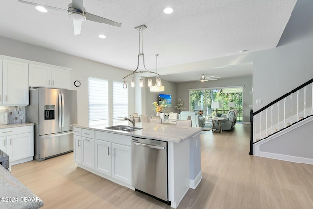 kitchen with ceiling fan, sink, stainless steel appliances, white cabinets, and light wood-type flooring