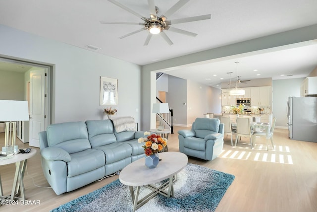 living room featuring ceiling fan and light hardwood / wood-style flooring