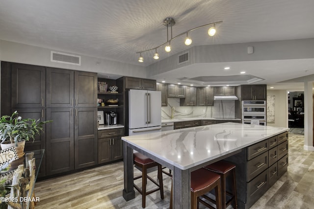 1 John Anderson Dr Unit 103, Ormond Beach, FL 32176 - kitchen with white appliances, open shelves, light wood-style flooring, a breakfast bar area, and light stone countertops