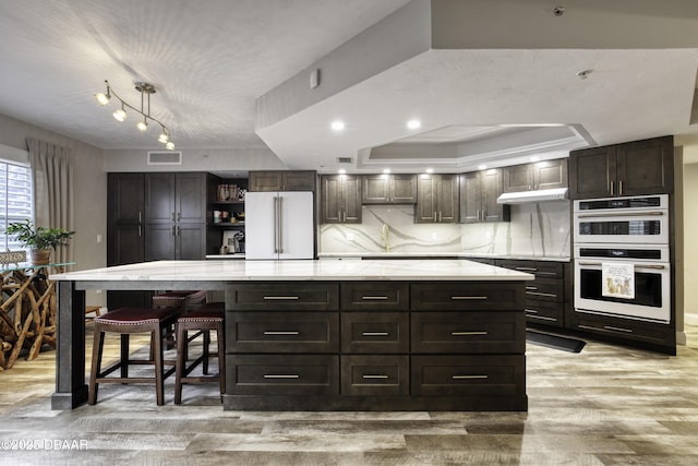 1 John Anderson Dr Unit 103, Ormond Beach, FL 32176 - kitchen featuring freestanding refrigerator, double oven, light wood finished floors, dark brown cabinets, and a spacious island