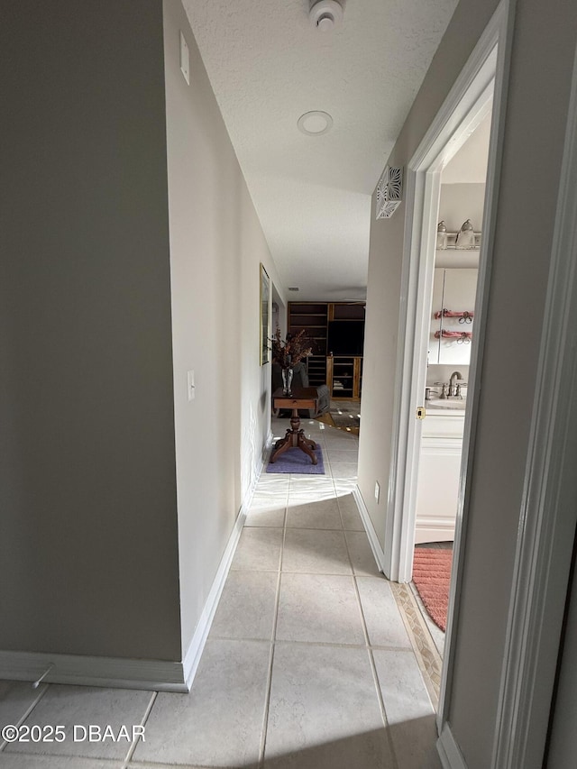 corridor featuring light tile patterned floors and sink