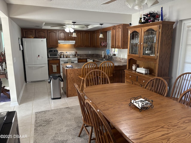 dining area featuring ceiling fan, sink, light tile patterned floors, and a textured ceiling