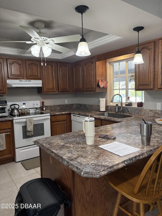 kitchen featuring a breakfast bar, decorative light fixtures, sink, a tray ceiling, and white appliances