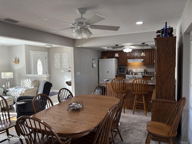 tiled dining room featuring ceiling fan and a textured ceiling