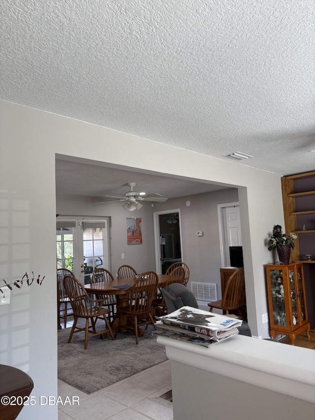 tiled dining area featuring a textured ceiling and ceiling fan