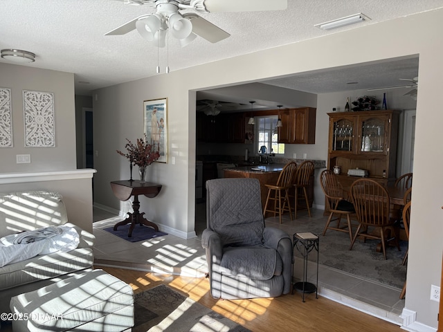 living room with sink, a textured ceiling, and light wood-type flooring