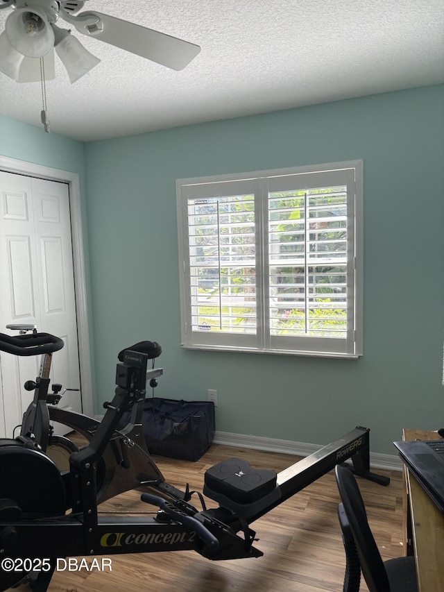 exercise room featuring ceiling fan, hardwood / wood-style floors, and a textured ceiling