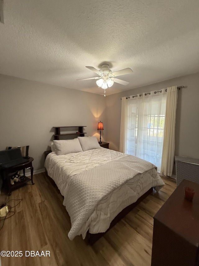 bedroom with ceiling fan, wood-type flooring, and a textured ceiling