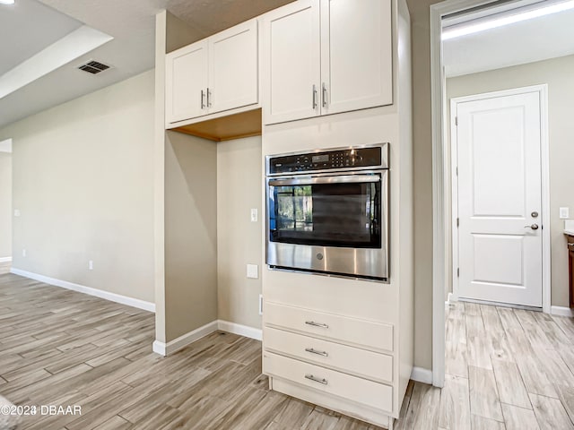 kitchen featuring white cabinetry, light hardwood / wood-style floors, and oven