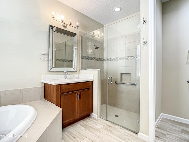 bathroom featuring vanity, a textured ceiling, hardwood / wood-style flooring, and separate shower and tub